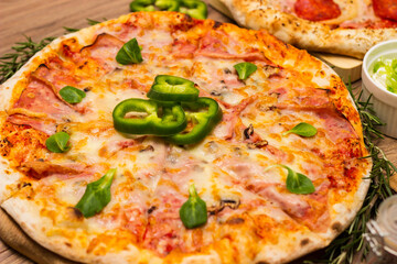 Two different pizza with ingredients on rustic background. Pepperoni pizza and pizza Capricciosa with mozzarella cheese, ham, tomato sauce, salami, mushroom, pepper, spices and fresh basil
