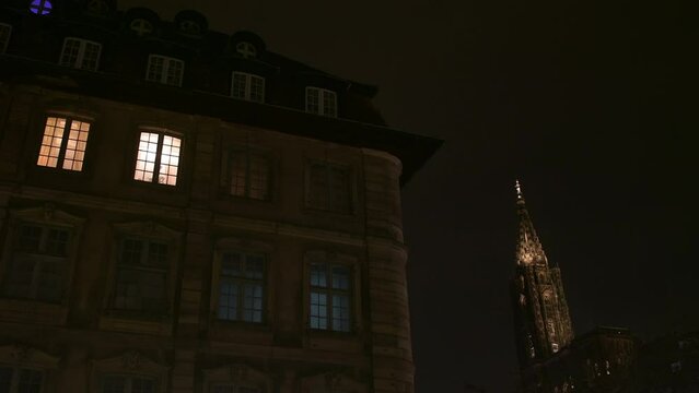 beautiful old bourgeois Haussmannian building in central Strasbourg French city France, housing luxury apartments or offices with lights at night - Cathedrale Notre-Dame de Strasbourg spire in backgro