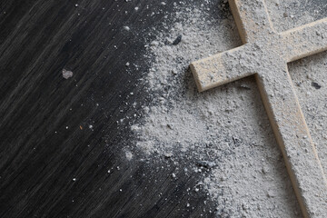 Small wood cross covered with ashes on a dark wood background with copy space