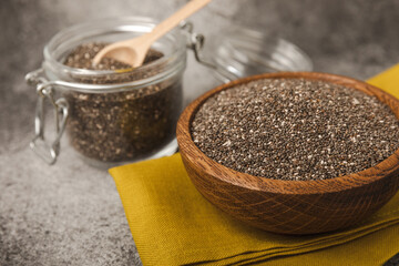Chia seeds in bowls, spoons and glass jars on a black marble background. SUPERFOOD and antioxidant. Healthy food concept. Gluten free. Copy space.