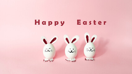 Obraz na płótnie Canvas Happy Easter Day. Three cute bunnies made of white chicken eggs isolated on a light pink pastel background.