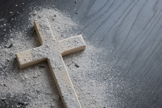 Wood cross covered with ashes on a dark wood background with copy space