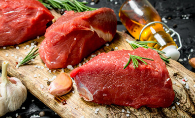 Raw meat. Pieces of fresh beef with spices, garlic and rosemary.