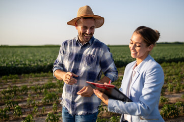 Business woman and farmer signing documents in field
