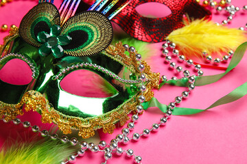 Carnival mask for Mardi Gras celebration with feathers and beads on pink background, closeup