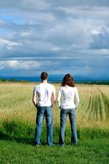 Rear view of young couple overlooking farmland.