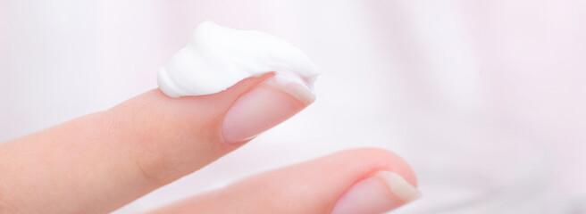 Young woman using moisturizer cream on her hands to take care of her skin	