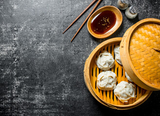 Fragrant manta dumplings in a bamboo steamer with soy sauce.