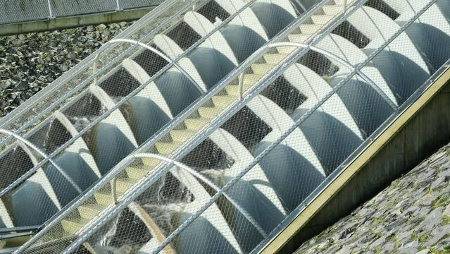 Closeup of grey turning metal screw pumps to pump water from low to high. Also known as Archimedes screw pump or water screw