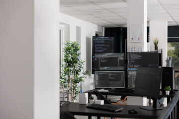 Empty programming office with computer monitors on desk, computers in background running html code and algorithms on terminal window. Firewall network servers in software company.