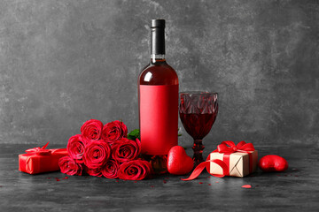 Bottle of wine, rose flowers, glass and gift on black table. Valentine's Day celebration
