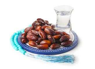 Plate with dried dates, glass of water and prayer beads for Ramadan on white background