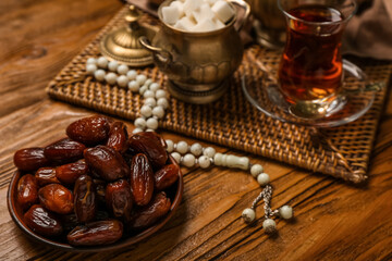 Plate with dates and prayer beads on wooden background, closeup