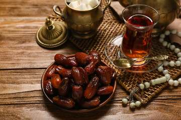 Plate with dates, prayer beads and glass of tea for Ramadan on wooden background, closeup