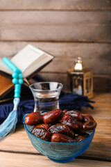 Bowl with dried dates for Ramadan on wooden table, closeup