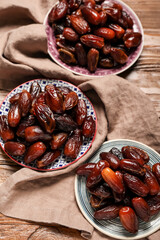 Plates with dried dates and napkin for Ramadan on wooden background