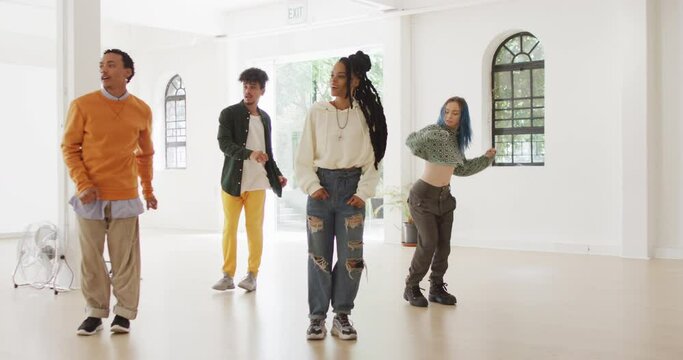 Happy diverse male and female dancers dancing in dance studio, slow motion