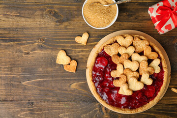 Tray with sweet strawberry pie, cookie hearts, gift and bowl of brown sugar for Valentine's day on wooden background