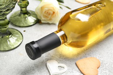 Bottle of wine, glasses, rose flower and hearts on grey table. Valentine's Day celebration