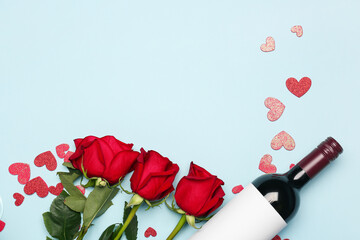 Bottle of wine and rose flowers on blue background. Valentine's Day celebration