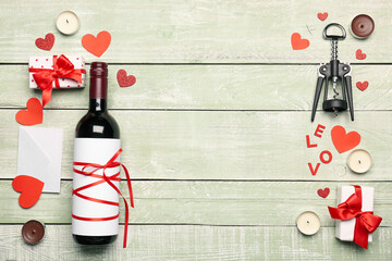 Composition with bottle of wine, glasses, gift and candles on green wooden background. Valentine's...