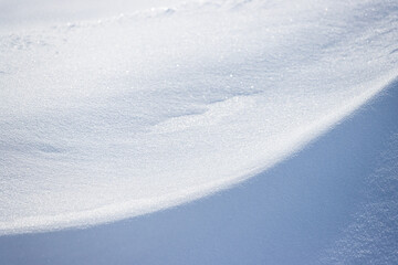 Beautiful winter background with snowy ground. Natural snow texture. Wind sculpted patterns on snow surface. Closeup top view with copy space.