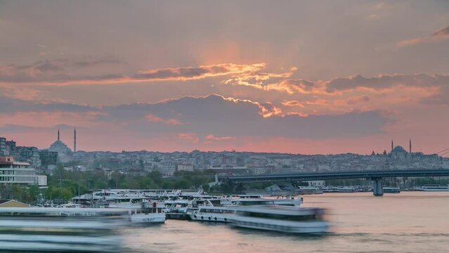 Many passenger ferrys near boat station in the Bosphorus and Golden Horn at sunset timelapse, Istanbul skyline, Turkey. Mosque and bridge on background with reflection on water at sping evening