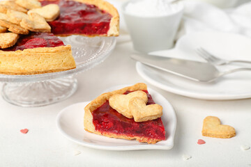 Stand and heart-shaped plate with sweet strawberry pie and cookie hearts for Valentine's day on white table
