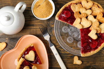 Sweet strawberry pie, cookie hearts, teapot and bowl of brown sugar on wooden table