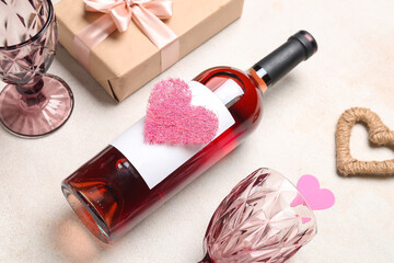 Obraz na płótnie Canvas Composition with bottle of wine, glasses, gift and hearts on white grunge background. Valentine's Day celebration