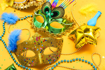 Carnival masks with beads, confetti and balloons on yellow background