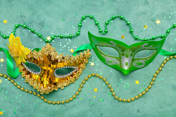 Carnival masks with beads and confetti on green background
