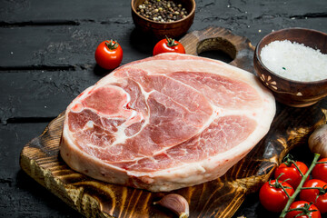 Big raw pork steak with tomatoes and spices.