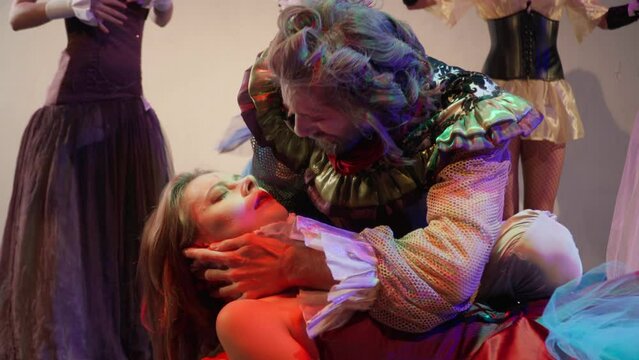 Crying grieving actor kissing actress as woman waking up looking at camera with evil facial expression. Professional Caucasian performers playing role in show on theater stage