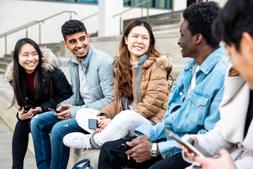 Happy group of friends in the city using mobile phones and laughing together