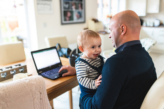Happy baby boy with hid father working from home