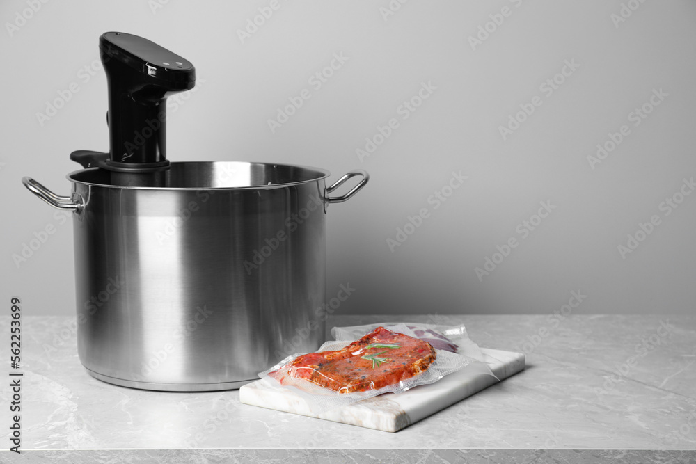 Wall mural Thermal immersion circulator in pot and vacuum packing with meat on light grey table, space for text. Sous vide cooking - Wall murals