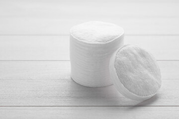 Stack of clean cotton pads on white wooden table, closeup. Space for text