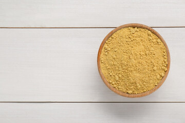 Bowl of aromatic mustard powder on white wooden table, top view. Space for text