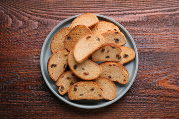 Plate of sweet hard chuck crackers with raisins on wooden table, top view