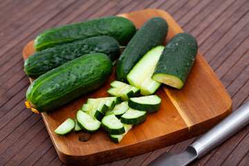 Ripe green cut cucumbers on wooden background, nobody
