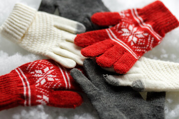 Warm gloves on a white background. Red and grey gloves. Snowy background. Close up.