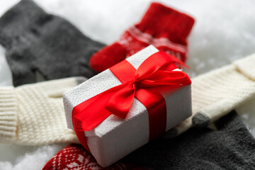 New Year gift with gloves. Warm gloves on a white background. Snowy background. Close up.