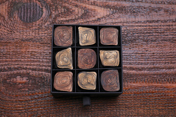Box of tasty chocolate candies on wooden table, top view
