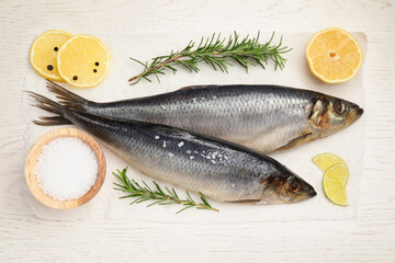 Delicious salted herrings, rosemary, salt and lemon on white wooden table, flat lay
