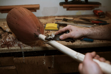 instrument (baglama) master is doing his instrument . instrument and workers hands close-up . selective focus.