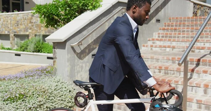 Happy african american businessman going up stairs with bike, slow motion