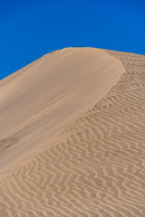 A sand dune against a blue sky