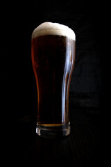 A glass of beer on a dark background.