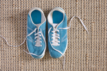 Bright blue sneakers of a natural look, with slightly dirty socks and scuffs from sports, stand on a natural jute and cotton carpet. Sports, home workouts